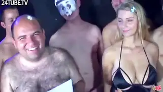 Сочная блондинка с большими сиськами отсасывает сразу нескольким хуям и получает огромную порцию спермы.